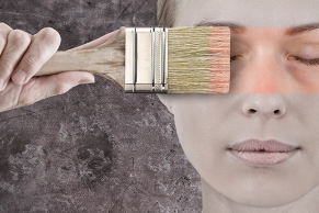 Frau mit einem Malerpinsel schminkt Ihr Gesicht