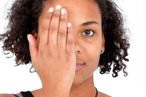 Junge-farbige-Frau-haet-sich-mit-der-Hand-ein-Auge-zu