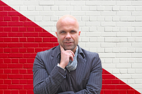 Mann-vor-einer-rot-weissen-Steinwand